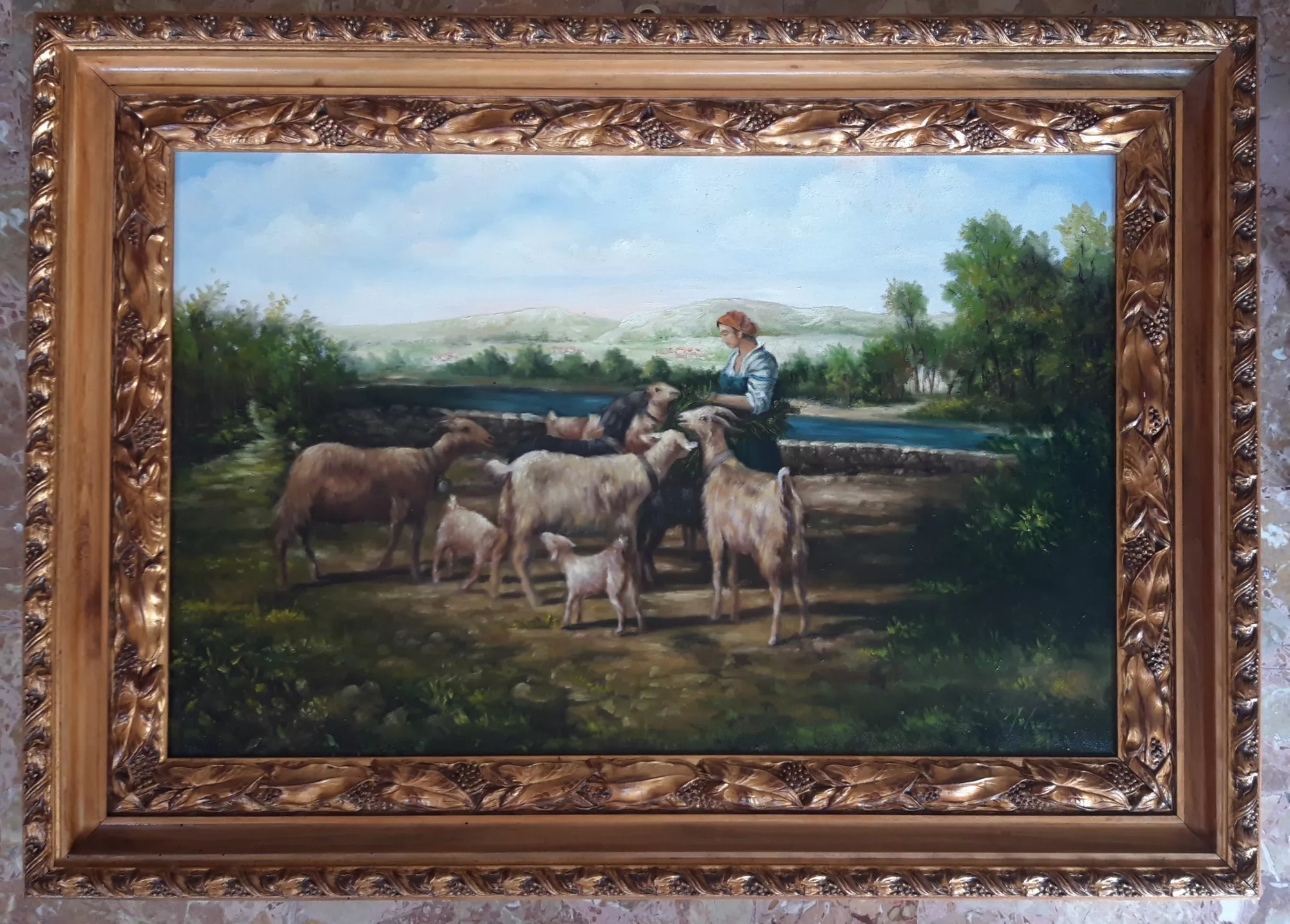 Capre-e-pastorella-al-pascolo-Aly-Mohsen "Quadro di Ay Mohsen realizzato ad Olio con pennello. Il titolo è Capre e pastorella al pascolo e rientra nella categoria C'era una volta. In Capre e pastorella al pascolo, Aly Mohsen sviluppa una scena figurativa di ispirazione pastorale dedicata al rapporto armonico tra essere umano, animali e paesaggio naturale. La giovane pastorella, collocata al centro della composizione, guida e nutre il gregge in un gesto semplice e quotidiano che assume valore simbolico, richiamando temi di cura, continuità e rispetto della natura. La composizione è aperta e ben strutturata: il paesaggio si estende in profondità attraverso colline, corsi d’acqua e vegetazione, creando un equilibrio visivo tra figura umana e ambiente circostante. La disposizione circolare delle capre attorno alla pastorella introduce un ritmo armonico che accompagna lo sguardo e rafforza il senso di comunità e protezione. La pittura si distingue per la resa realistica degli animali, la pennellata morbida e controllata e l’uso misurato del colore, capace di restituire un’atmosfera serena e senza tempo. Il soggetto pastorale si inserisce nel solco della tradizione figurativa europea, reinterpretata in chiave contemporanea attraverso una narrazione chiara e contemplativa. Il dipinto è completato da una cornice dorata finemente lavorata, di gusto classico, che ne valorizza la composizione e ne rafforza il carattere espositivo e museale."