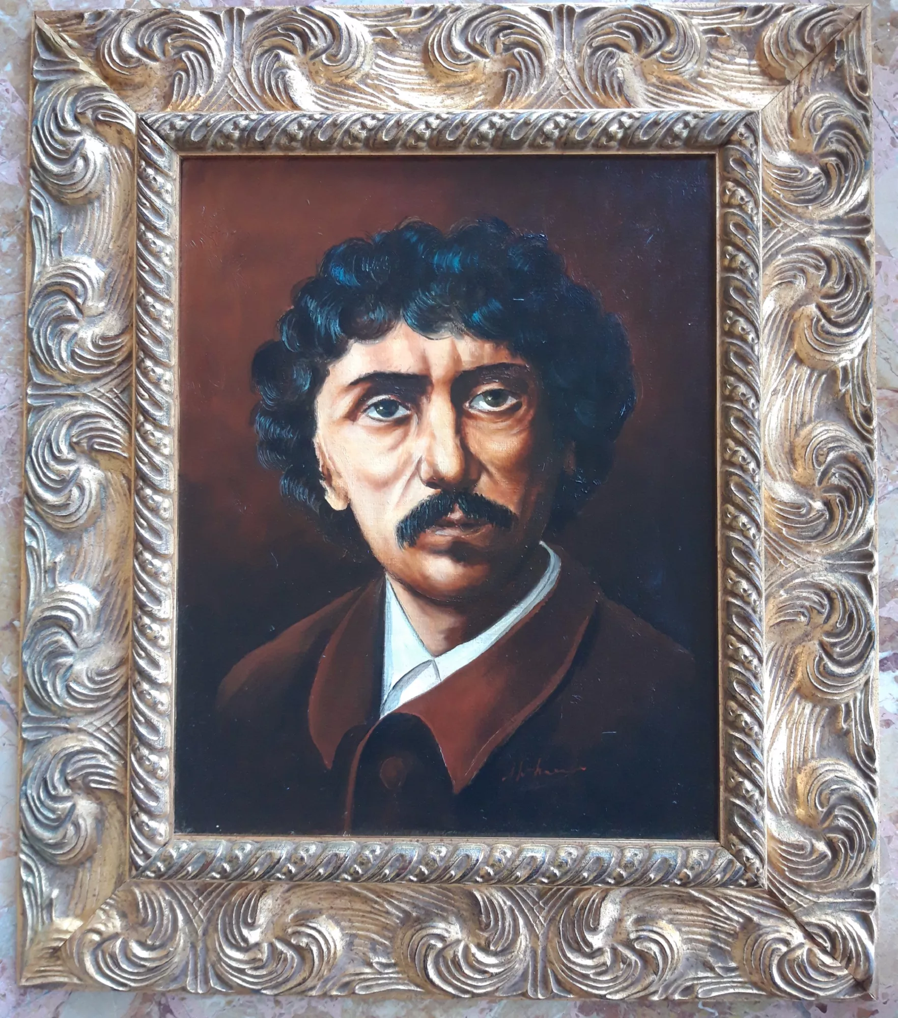 Ritratto-di-Charles-Garnier-Aly-Mohsen "Quadro di Ay Mohsen realizzato ad Olio con pennello. Il titolo è Ritratto di Charles Garnier e rientra nella categoria Ritratti. Nel Ritratto di Charles Garnier Aly Mohsen affronta il genere del ritratto storico con rigore formale e profonda attenzione psicologica. Il celebre architetto francese, autore dell’Opéra di Parigi, è raffigurato in una posa sobria e concentrata, lontana da ogni enfasi celebrativa e orientata invece alla restituzione della sua statura intellettuale e creativa. Il volto emerge con forza da uno sfondo scuro e neutro, che concentra lo sguardo sull’espressione intensa e pensosa del soggetto. Gli occhi, leggermente sollevati, suggeriscono riflessione e visione progettuale, mentre i tratti marcati del volto e i baffi definiscono un carattere deciso e consapevole. Mohsen supera la mera somiglianza fisionomica per costruire un’immagine capace di trasmettere identità, autorevolezza e profondità interiore. La pittura è compatta e controllata, con una resa attenta dell’incarnato e delle transizioni luminose. La luce, misurata e direzionale, modella il volto con sobrietà, creando volume e profondità attraverso passaggi tonali calibrati. La tavolozza, dominata da bruni, ocra e neri caldi, rafforza il carattere serio e monumentale del ritratto, in dialogo con la tradizione del ritratto europeo ottocentesco. L’opera è completata da una cornice dorata originale, ampia e riccamente decorata, che conferisce al dipinto una forte presenza espositiva e un carattere museale, valorizzando il soggetto e il suo rilievo storico. Opera figurativa originale di Aly Mohsen, il Ritratto di Charles Garnier si inserisce nel ciclo dedicato ai grandi protagonisti della storia culturale europea, distinguendosi per solidità formale, chiarezza narrativa e intensità psicologica."