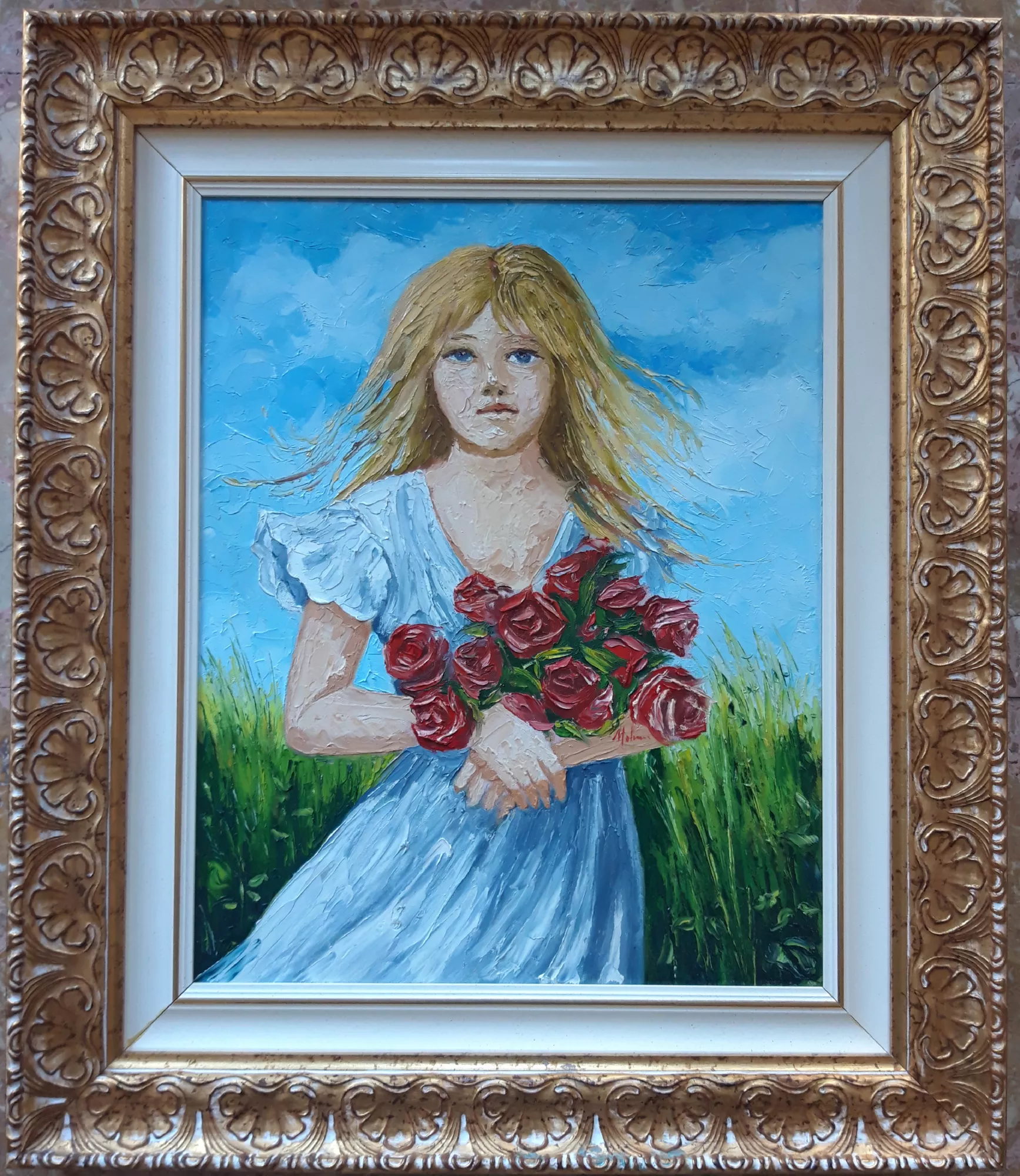 La-ragazza-con-le-rose-Aly-Mohsen "Quadro di Ay Mohsen realizzato ad Olio con spatola. Il titolo è La ragazza con le rose e rientra nella categoria Ritratti. In La ragazza con le rose, Aly Mohsen realizza un ritratto figurativo di forte intensità espressiva, costruito integralmente attraverso l’uso della spatola, tecnica che conferisce all’opera una marcata presenza materica e una vibrazione emotiva immediata. La giovane figura femminile emerge frontalmente da un paesaggio aperto, stringendo tra le braccia un mazzo di rose rosse, elemento simbolico che richiama sentimento, vitalità e passaggio interiore. Lo sguardo diretto e silenzioso della ragazza instaura un dialogo immediato con l’osservatore. I tratti del volto, modellati con impasti decisi e stratificazioni dense, evitano ogni idealizzazione, restituendo un’espressione autentica, sospesa tra delicatezza e determinazione. I capelli mossi dal vento e l’abito chiaro sono resi con colpi di spatola energici, che suggeriscono movimento e libertà, accentuando la dimensione emotiva della scena. La tavolozza cromatica è luminosa e contrastata: l’azzurro del cielo e del vestito dialoga con il verde intenso della vegetazione, mentre il rosso profondo delle rose, applicato con maggiore spessore, diventa il fulcro visivo e simbolico della composizione. Il colore, lavorato come materia viva, genera rilievi e vibrazioni che catturano la luce e rendono la superficie pittorica dinamica e pulsante. Il paesaggio, pur essenziale, partecipa attivamente alla costruzione dell’immagine. Realizzato anch’esso a spatola, rafforza l’unità tra figura e natura, suggerendo uno spazio aperto e arioso, carico di respiro e di attesa. L’insieme trasmette una sensazione di tempo sospeso, cifra ricorrente nella poetica figurativa di Mohsen. La cornice ampia e decorata, di gusto classico, crea un raffinato contrasto con la forza espressiva della pittura materica, valorizzando l’opera e conferendole una presenza espositiva di carattere museale. Opera figurativa originale di Aly Mohsen, La ragazza con le rose si inserisce nel percorso dedicato alla figura femminile e alla dimensione emotiva della memoria, distinguendosi per coerenza formale, intensità cromatica e solidità espressiva."