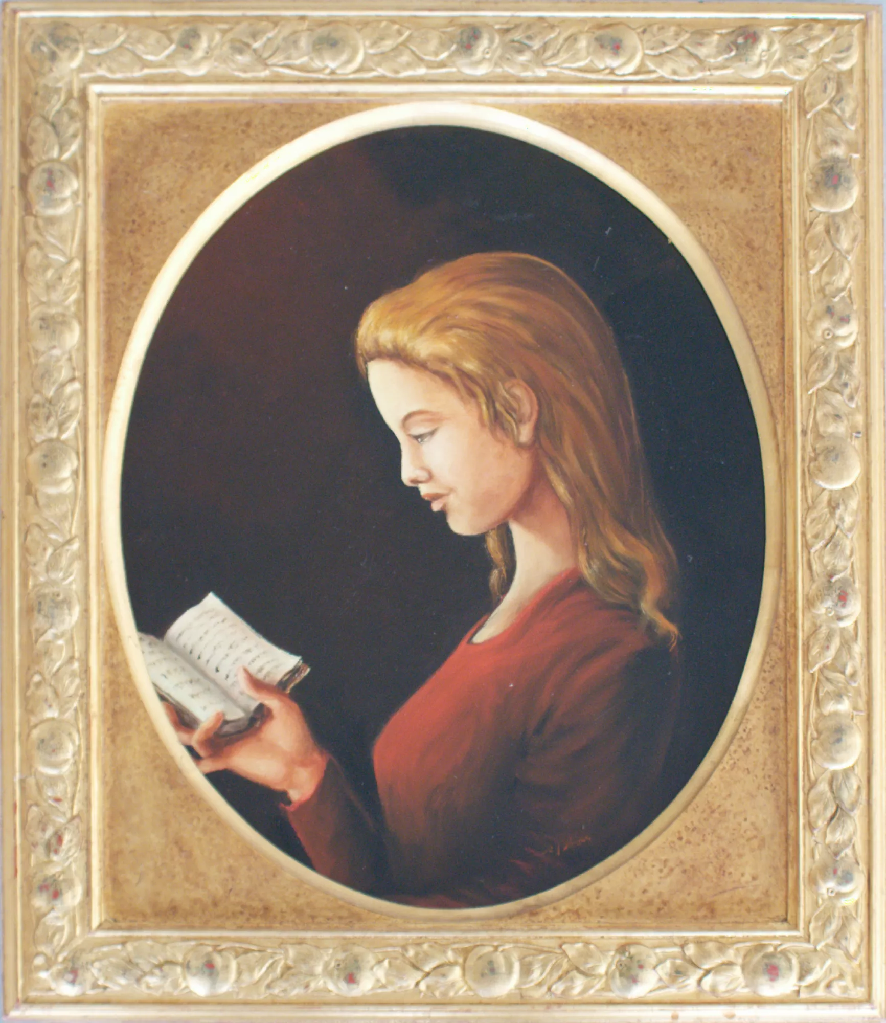 Girl-reading-Aly-Mohsen "Painting by Aly Mohsen, executed in Oil on canvas (brush). The title is Girl reading and it belongs to the category Portraits. In Girl reading, Aly Mohsen creates a work of deep emotional delicacy, in which the simple act of reading becomes a moment of recollection, silence, and introspection. The young figure is portrayed in profile, captured in a state of total concentration as she holds a small book in her hands, engaged in an intimate and personal dialogue with words. The composition, enclosed within an oval format, consciously recalls the tradition of classical portraiture and lends the image a timeless quality. The dark, neutral background isolates the figure, allowing light to gently shape the face, hair, and hands—the true expressive focal points of the painting. The slightly bowed head and absorbed gaze convey calm, restraint, and inner depth. The chromatic palette is restrained and elegant: warm flesh tones and hair colors interact with the deep red of the dress, creating a refined balance against the dark background. Soft, controlled light guides the viewer’s eye toward the book, a symbolic element associated with knowledge, meditation, and inner growth. Mohsen’s figurative painting is distinguished by the refinement of its anatomical rendering and the subtle handling of tonal transitions, which lend naturalness to the volumes and a sense of suspended stillness. The absence of narrative excess allows atmosphere itself to become the core meaning of the work. The richly decorated frame, inspired by classical motifs, plays a fundamental role in dialogue with the painting: it enhances the work’s formal elegance and reinforces its contemplative and museum-like presence. An original figurative work by Aly Mohsen, Girl reading fits coherently within his artistic exploration of the female figure as a symbol of interiority, grace, and quiet harmony."