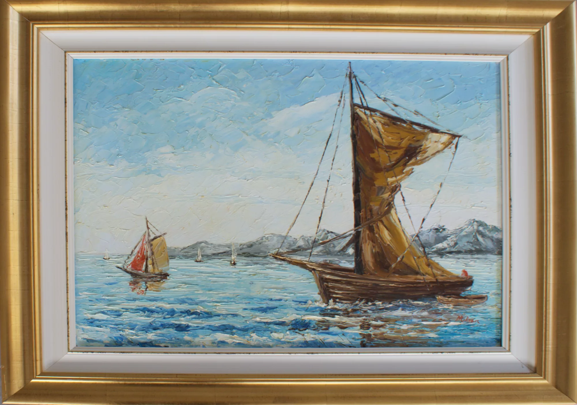 Barche-con-montagne-sullo-sfondo-Aly-Mohsen "Quadro di Ay Mohsen realizzato ad Olio con spatola. Il titolo è Barche con montagne sullo sfondo e rientra nella categoria Il mare. Paesaggio marino con barche e montagne è un dipinto realizzato con tecnica a spatola in cui Aly Mohsen affida alla materia pittorica il racconto del movimento del mare e della quiete dell’orizzonte. In primo piano, una barca a vela domina la composizione con la vela gonfiata dal vento, costruita attraverso spessori di colore che ne sottolineano forza, stabilità e presenza scenica. Le increspature dell’acqua, modellate con colpi energici di spatola, trasmettono dinamismo e profondità spaziale. Sul lato sinistro, una seconda imbarcazione più distante accompagna lo sguardo verso il centro della scena, creando un equilibrio visivo misurato e un ritmo compositivo naturale. Sullo sfondo, le montagne delineano l’orizzonte marino, introducendo solidità e ampiezza al paesaggio e rafforzando il dialogo tra mare e terra. Il cielo, luminoso e arioso, è costruito attraverso sovrapposizioni materiche di azzurri e bianchi che amplificano la percezione di luce, spazio e apertura atmosferica. La cornice dorata valorizza i toni caldi delle imbarcazioni e il contrasto con i blu del mare, esaltando l’intensità cromatica e l’equilibrio complessivo dell’opera."