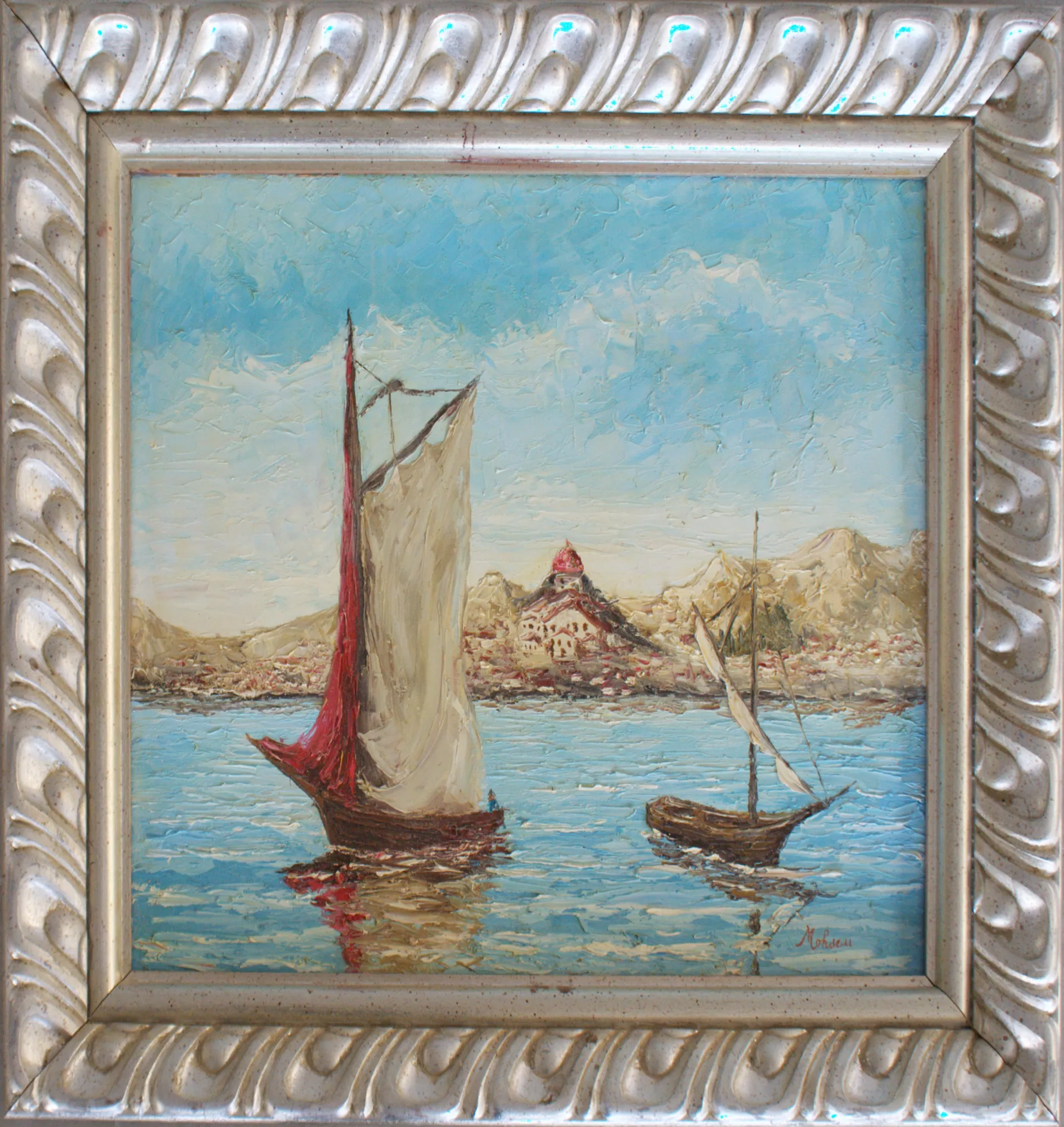 Boats-with-Sanremo-in-the-background-Aly-Mohsen "Painting by Aly Mohsen, executed in Oil on canvas (palette knife). The title is Boats with Sanremo in the background and it belongs to the category The Sea. Boats with Sanremo in the background is an original painting by Aly Mohsen depicting a seascape with sailboats and the city of Sanremo in the distance, a clear reference to the Ligurian Riviera—an area closely connected to the artist’s pictorial research. The work is executed in oil on canvas using a palette-knife technique, a distinctive hallmark of Mohsen’s style, which gives the pictorial surface strong material presence and a vibrant, luminous quality. In the foreground, two traditional boats move across calm, reflective waters. The main boat, with a light-colored sail accompanied by a red sail, dominates the composition and immediately draws the viewer’s eye, while a smaller, more distant boat introduces visual balance and perspectival depth. Dense, dynamic palette-knife strokes shape the water through reflections and gentle ripples, while the blue sky, built with broad textured passages, enhances the sense of space and openness. In the background, the urban profile of Sanremo emerges clearly, recognizable by the sanctuary with its central dome set among the hills. This architectural element adds narrative and territorial value to the scene, creating a harmonious dialogue between the seascape, the boats, and the historical identity of the place. The overall composition offers a balanced and timeless vision of the Mediterranean landscape. The painting is completed by a finely crafted silver-toned frame with classical relief motifs, enclosing the work with elegance and restraint. The frame harmonizes with the painting’s tonal range, enhancing its luminosity and expressive strength, and makes the artwork immediately suitable for display in refined interiors and private collections."