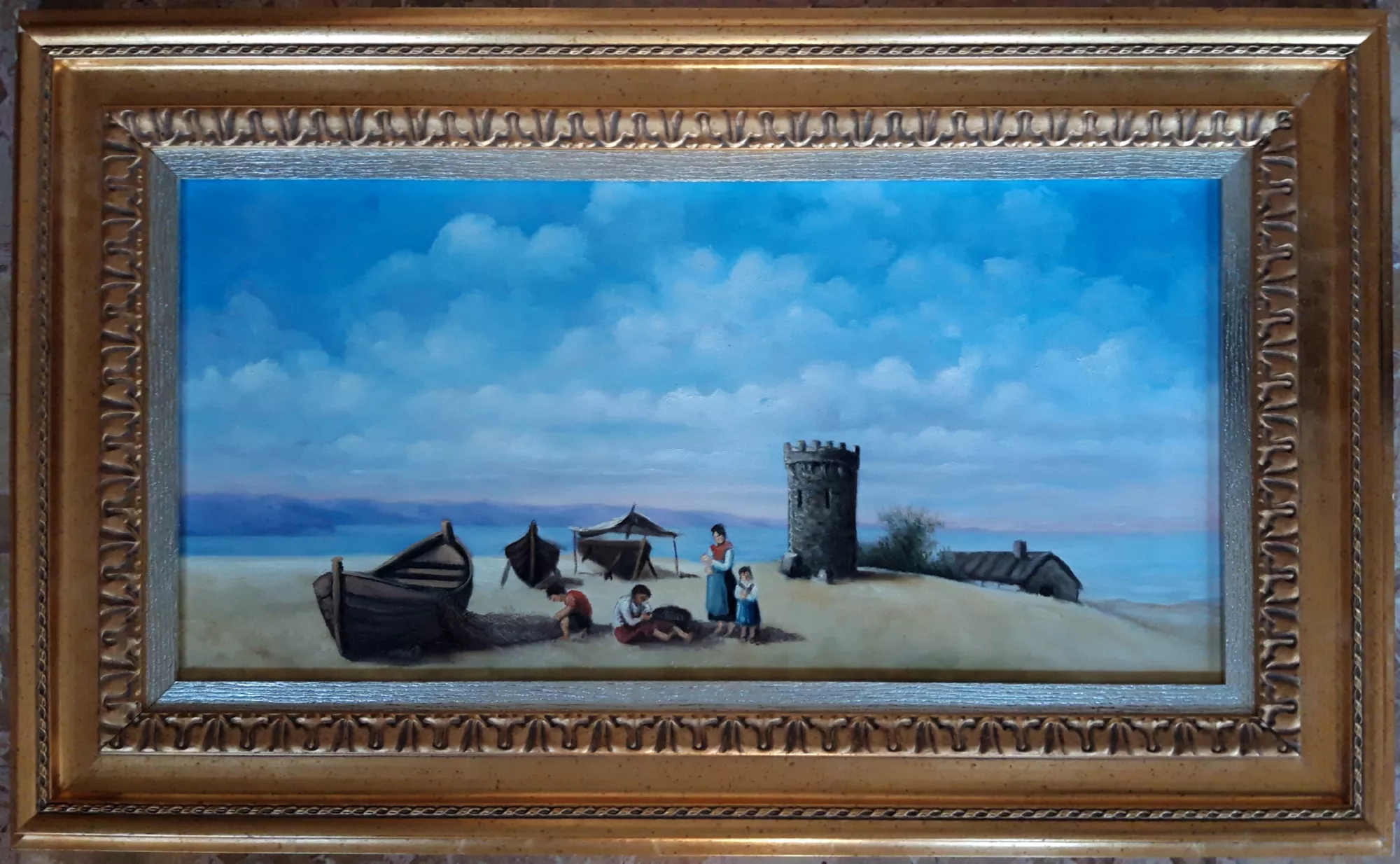 Fisherman’s-family-on-the-beach-Aly-Mohsen "Painting by Aly Mohsen, executed in Oil on canvas (brush). The title is Fisherman’s family on the beach and it belongs to the category The Sea. Original work by Aly Mohsen depicting a scene of everyday life on the shoreline, offering a calm and poetic interpretation of the world of fishermen and their families. The composition is defined by a balanced narrative structure and a measured figurative language, through which the artist captures a moment of quiet closely connected to the domestic and communal dimension of coastal life. At the center of the scene, a family group is gathered on the sand, portrayed during a moment of rest and shared presence. The figures, rendered with careful attention to gesture and interpersonal relationships, convey a sense of harmony and continuity, suggesting the deep bond between work, affection, and the marine environment. Children and adults are naturally integrated into the space, becoming an essential part of both the landscape and the visual narrative. In the background, fishing boats pulled ashore, a stone coastal tower, and modest village structures appear, providing the scene with a clear territorial reference linked to the Ligurian Riviera and, more broadly, to the Mediterranean coastal tradition. The calm sea and open horizon expand the spatial depth, while the wide and luminous sky is constructed through soft gradations of blue and white achieved with controlled brushwork and without pronounced textural effects. The diffused and even light envelops the entire composition, creating an atmosphere of stability and serenity that dialogues with the artist’s more dramatic seascapes. In this work, Aly Mohsen adopts a quiet narrative approach grounded in continuity, tradition, and everyday life—recurring themes within his figurative research. The painting is completed by a classical-style frame with a gilded finish and raised decorative details. The inner silver-toned border introduces a balanced chromatic contrast that guides the viewer’s eye toward the central scene, enhancing the tones of the sky and the beach and giving the artwork a harmonious and resolved visual presence."
