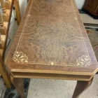 "Opera di Ay Mohsen realizzato con la tecnica dell'intarsio. Il titolo è Scrivania neoclassica e rientra nella categoria Ebanisteria Monumentale. Questa scrivania neoclassica intarsiata di Aly Mohsen si configura come opera di alta ebanisteria artistica, concepita come manufatto unitario in cui funzione e costruzione formale sono integrate in una struttura di carattere decorativo e architettonico. L’opera si colloca nel solco della tradizione dell’arredo classico europeo, riletta attraverso un controllo rigoroso dei materiali e della composizione. Il piano è realizzato in piuma di mogano selezionata, caratterizzata da una venatura simmetrica e continua che definisce una superficie compatta e visivamente coerente. L’area centrale è incorniciata da un articolato sistema di intarsi in acero chiaro, disposti secondo un disegno perimetrale di gusto neoclassico, con motivi floreali e fitomorfi collocati agli angoli e nei punti mediani dei lati. Il rapporto tra la decorazione intarsiata e la marezzatura naturale del mogano è costruito per continuità ritmica e bilanciamento visivo. I bordi del piano sono rifiniti in noce chiaro, introducendo un passaggio cromatico graduale tra superficie e struttura. Il corpo della scrivania e i cassetti sono realizzati in noce scuro, materiale che conferisce solidità visiva e coerenza tonale all’insieme, contribuendo alla lettura architettonica del mobile. Le gambe smontabili sono costruite con un’anima in mogano lamellare, successivamente rivestita in radica di quercia. Su ciascuna gamba sono presenti intarsi verticali in acero chiaro, impostati come elementi ornamentali continui che accentuano lo sviluppo verticale e il carattere scultoreo della struttura. Il bordo perimetrale del piano, trattato come cornice funzionale dell’intera composizione, svolge un ruolo di contenimento visivo e di definizione spaziale dell’opera, delimitando la superficie intarsiata e contribuendo alla stabilità formale e percettiva della scrivania.""Quadro di Ay Mohsen realizzato ad Intarsio. Il titolo è Scrivania neoclassica e rientra nella categoria Ebanisteria Monumentale. Questa scrivania neoclassica intarsiata di Aly Mohsen si configura come opera di alta ebanisteria artistica, concepita come manufatto unitario in cui funzione e costruzione formale sono integrate in una struttura di carattere decorativo e architettonico. L’opera si colloca nel solco della tradizione dell’arredo classico europeo, riletta attraverso un controllo rigoroso dei materiali e della composizione. Il piano è realizzato in piuma di mogano selezionata, caratterizzata da una venatura simmetrica e continua che definisce una superficie compatta e visivamente coerente. L’area centrale è incorniciata da un articolato sistema di intarsi in acero chiaro, disposti secondo un disegno perimetrale di gusto neoclassico, con motivi floreali e fitomorfi collocati agli angoli e nei punti mediani dei lati. Il rapporto tra la decorazione intarsiata e la marezzatura naturale del mogano è costruito per continuità ritmica e bilanciamento visivo. I bordi del piano sono rifiniti in noce chiaro, introducendo un passaggio cromatico graduale tra superficie e struttura. Il corpo della scrivania e i cassetti sono realizzati in noce scuro, materiale che conferisce solidità visiva e coerenza tonale all’insieme, contribuendo alla lettura architettonica del mobile. Le gambe smontabili sono costruite con un’anima in mogano lamellare, successivamente rivestita in radica di quercia. Su ciascuna gamba sono presenti intarsi verticali in acero chiaro, impostati come elementi ornamentali continui che accentuano lo sviluppo verticale e il carattere scultoreo della struttura. Il bordo perimetrale del piano, trattato come cornice funzionale dell’intera composizione, svolge un ruolo di contenimento visivo e di definizione spaziale dell’opera, delimitando la superficie intarsiata e contribuendo alla stabilità formale e percettiva della scrivania.""Quadro di Ay Mohsen realizzato ad Intarsio. Il titolo è Scrivania neoclassica e rientra nella categoria Ebanisteria Monumentale. Questa scrivania neoclassica intarsiata di Aly Mohsen si configura come opera di alta ebanisteria artistica, concepita come manufatto unitario in cui funzione e costruzione formale sono integrate in una struttura di carattere decorativo e architettonico. L’opera si colloca nel solco della tradizione dell’arredo classico europeo, riletta attraverso un controllo rigoroso dei materiali e della composizione. Il piano è realizzato in piuma di mogano selezionata, caratterizzata da una venatura simmetrica e continua che definisce una superficie compatta e visivamente coerente. L’area centrale è incorniciata da un articolato sistema di intarsi in acero chiaro, disposti secondo un disegno perimetrale di gusto neoclassico, con motivi floreali e fitomorfi collocati agli angoli e nei punti mediani dei lati. Il rapporto tra la decorazione intarsiata e la marezzatura naturale del mogano è costruito per continuità ritmica e bilanciamento visivo. I bordi del piano sono rifiniti in noce chiaro, introducendo un passaggio cromatico graduale tra superficie e struttura. Il corpo della scrivania e i cassetti sono realizzati in noce scuro, materiale che conferisce solidità visiva e coerenza tonale all’insieme, contribuendo alla lettura architettonica del mobile. Le gambe smontabili sono costruite con un’anima in mogano lamellare, successivamente rivestita in radica di quercia. Su ciascuna gamba sono presenti intarsi verticali in acero chiaro, impostati come elementi ornamentali continui che accentuano lo sviluppo verticale e il carattere scultoreo della struttura. Il bordo perimetrale del piano, trattato come cornice funzionale dell’intera composizione, svolge un ruolo di contenimento visivo e di definizione spaziale dell’opera, delimitando la superficie intarsiata e contribuendo alla stabilità formale e percettiva della scrivania."