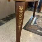 "Opera di Ay Mohsen realizzato con la tecnica dell'intarsio. Il titolo è Scrivania neoclassica e rientra nella categoria Ebanisteria Monumentale. Questa scrivania neoclassica intarsiata di Aly Mohsen si configura come opera di alta ebanisteria artistica, concepita come manufatto unitario in cui funzione e costruzione formale sono integrate in una struttura di carattere decorativo e architettonico. L’opera si colloca nel solco della tradizione dell’arredo classico europeo, riletta attraverso un controllo rigoroso dei materiali e della composizione. Il piano è realizzato in piuma di mogano selezionata, caratterizzata da una venatura simmetrica e continua che definisce una superficie compatta e visivamente coerente. L’area centrale è incorniciata da un articolato sistema di intarsi in acero chiaro, disposti secondo un disegno perimetrale di gusto neoclassico, con motivi floreali e fitomorfi collocati agli angoli e nei punti mediani dei lati. Il rapporto tra la decorazione intarsiata e la marezzatura naturale del mogano è costruito per continuità ritmica e bilanciamento visivo. I bordi del piano sono rifiniti in noce chiaro, introducendo un passaggio cromatico graduale tra superficie e struttura. Il corpo della scrivania e i cassetti sono realizzati in noce scuro, materiale che conferisce solidità visiva e coerenza tonale all’insieme, contribuendo alla lettura architettonica del mobile. Le gambe smontabili sono costruite con un’anima in mogano lamellare, successivamente rivestita in radica di quercia. Su ciascuna gamba sono presenti intarsi verticali in acero chiaro, impostati come elementi ornamentali continui che accentuano lo sviluppo verticale e il carattere scultoreo della struttura. Il bordo perimetrale del piano, trattato come cornice funzionale dell’intera composizione, svolge un ruolo di contenimento visivo e di definizione spaziale dell’opera, delimitando la superficie intarsiata e contribuendo alla stabilità formale e percettiva della scrivania.""Quadro di Ay Mohsen realizzato ad Intarsio. Il titolo è Scrivania neoclassica e rientra nella categoria Ebanisteria Monumentale. Questa scrivania neoclassica intarsiata di Aly Mohsen si configura come opera di alta ebanisteria artistica, concepita come manufatto unitario in cui funzione e costruzione formale sono integrate in una struttura di carattere decorativo e architettonico. L’opera si colloca nel solco della tradizione dell’arredo classico europeo, riletta attraverso un controllo rigoroso dei materiali e della composizione. Il piano è realizzato in piuma di mogano selezionata, caratterizzata da una venatura simmetrica e continua che definisce una superficie compatta e visivamente coerente. L’area centrale è incorniciata da un articolato sistema di intarsi in acero chiaro, disposti secondo un disegno perimetrale di gusto neoclassico, con motivi floreali e fitomorfi collocati agli angoli e nei punti mediani dei lati. Il rapporto tra la decorazione intarsiata e la marezzatura naturale del mogano è costruito per continuità ritmica e bilanciamento visivo. I bordi del piano sono rifiniti in noce chiaro, introducendo un passaggio cromatico graduale tra superficie e struttura. Il corpo della scrivania e i cassetti sono realizzati in noce scuro, materiale che conferisce solidità visiva e coerenza tonale all’insieme, contribuendo alla lettura architettonica del mobile. Le gambe smontabili sono costruite con un’anima in mogano lamellare, successivamente rivestita in radica di quercia. Su ciascuna gamba sono presenti intarsi verticali in acero chiaro, impostati come elementi ornamentali continui che accentuano lo sviluppo verticale e il carattere scultoreo della struttura. Il bordo perimetrale del piano, trattato come cornice funzionale dell’intera composizione, svolge un ruolo di contenimento visivo e di definizione spaziale dell’opera, delimitando la superficie intarsiata e contribuendo alla stabilità formale e percettiva della scrivania.""Quadro di Ay Mohsen realizzato ad Intarsio. Il titolo è Scrivania neoclassica e rientra nella categoria Ebanisteria Monumentale. Questa scrivania neoclassica intarsiata di Aly Mohsen si configura come opera di alta ebanisteria artistica, concepita come manufatto unitario in cui funzione e costruzione formale sono integrate in una struttura di carattere decorativo e architettonico. L’opera si colloca nel solco della tradizione dell’arredo classico europeo, riletta attraverso un controllo rigoroso dei materiali e della composizione. Il piano è realizzato in piuma di mogano selezionata, caratterizzata da una venatura simmetrica e continua che definisce una superficie compatta e visivamente coerente. L’area centrale è incorniciata da un articolato sistema di intarsi in acero chiaro, disposti secondo un disegno perimetrale di gusto neoclassico, con motivi floreali e fitomorfi collocati agli angoli e nei punti mediani dei lati. Il rapporto tra la decorazione intarsiata e la marezzatura naturale del mogano è costruito per continuità ritmica e bilanciamento visivo. I bordi del piano sono rifiniti in noce chiaro, introducendo un passaggio cromatico graduale tra superficie e struttura. Il corpo della scrivania e i cassetti sono realizzati in noce scuro, materiale che conferisce solidità visiva e coerenza tonale all’insieme, contribuendo alla lettura architettonica del mobile. Le gambe smontabili sono costruite con un’anima in mogano lamellare, successivamente rivestita in radica di quercia. Su ciascuna gamba sono presenti intarsi verticali in acero chiaro, impostati come elementi ornamentali continui che accentuano lo sviluppo verticale e il carattere scultoreo della struttura. Il bordo perimetrale del piano, trattato come cornice funzionale dell’intera composizione, svolge un ruolo di contenimento visivo e di definizione spaziale dell’opera, delimitando la superficie intarsiata e contribuendo alla stabilità formale e percettiva della scrivania.""Opera di Ay Mohsen realizzato con la tecnica dell'intarsio. Il titolo è Scrivania neoclassica e rientra nella categoria Ebanisteria Monumentale. Questa scrivania neoclassica intarsiata di Aly Mohsen si configura come opera di alta ebanisteria artistica, concepita come manufatto unitario in cui funzione e costruzione formale sono integrate in una struttura di carattere decorativo e architettonico. L’opera si colloca nel solco della tradizione dell’arredo classico europeo, riletta attraverso un controllo rigoroso dei materiali e della composizione. Il piano è realizzato in piuma di mogano selezionata, caratterizzata da una venatura simmetrica e continua che definisce una superficie compatta e visivamente coerente. L’area centrale è incorniciata da un articolato sistema di intarsi in acero chiaro, disposti secondo un disegno perimetrale di gusto neoclassico, con motivi floreali e fitomorfi collocati agli angoli e nei punti mediani dei lati. Il rapporto tra la decorazione intarsiata e la marezzatura naturale del mogano è costruito per continuità ritmica e bilanciamento visivo. I bordi del piano sono rifiniti in noce chiaro, introducendo un passaggio cromatico graduale tra superficie e struttura. Il corpo della scrivania e i cassetti sono realizzati in noce scuro, materiale che conferisce solidità visiva e coerenza tonale all’insieme, contribuendo alla lettura architettonica del mobile. Le gambe smontabili sono costruite con un’anima in mogano lamellare, successivamente rivestita in radica di quercia. Su ciascuna gamba sono presenti intarsi verticali in acero chiaro, impostati come elementi ornamentali continui che accentuano lo sviluppo verticale e il carattere scultoreo della struttura. Il bordo perimetrale del piano, trattato come cornice funzionale dell’intera composizione, svolge un ruolo di contenimento visivo e di definizione spaziale dell’opera, delimitando la superficie intarsiata e contribuendo alla stabilità formale e percettiva della scrivania.""Quadro di Ay Mohsen realizzato ad Intarsio. Il titolo è Scrivania neoclassica e rientra nella categoria Ebanisteria Monumentale. Questa scrivania neoclassica intarsiata di Aly Mohsen si configura come opera di alta ebanisteria artistica, concepita come manufatto unitario in cui funzione e costruzione formale sono integrate in una struttura di carattere decorativo e architettonico. L’opera si colloca nel solco della tradizione dell’arredo classico europeo, riletta attraverso un controllo rigoroso dei materiali e della composizione. Il piano è realizzato in piuma di mogano selezionata, caratterizzata da una venatura simmetrica e continua che definisce una superficie compatta e visivamente coerente. L’area centrale è incorniciata da un articolato sistema di intarsi in acero chiaro, disposti secondo un disegno perimetrale di gusto neoclassico, con motivi floreali e fitomorfi collocati agli angoli e nei punti mediani dei lati. Il rapporto tra la decorazione intarsiata e la marezzatura naturale del mogano è costruito per continuità ritmica e bilanciamento visivo. I bordi del piano sono rifiniti in noce chiaro, introducendo un passaggio cromatico graduale tra superficie e struttura. Il corpo della scrivania e i cassetti sono realizzati in noce scuro, materiale che conferisce solidità visiva e coerenza tonale all’insieme, contribuendo alla lettura architettonica del mobile. Le gambe smontabili sono costruite con un’anima in mogano lamellare, successivamente rivestita in radica di quercia. Su ciascuna gamba sono presenti intarsi verticali in acero chiaro, impostati come elementi ornamentali continui che accentuano lo sviluppo verticale e il carattere scultoreo della struttura. Il bordo perimetrale del piano, trattato come cornice funzionale dell’intera composizione, svolge un ruolo di contenimento visivo e di definizione spaziale dell’opera, delimitando la superficie intarsiata e contribuendo alla stabilità formale e percettiva della scrivania.""Quadro di Ay Mohsen realizzato ad Intarsio. Il titolo è Scrivania neoclassica e rientra nella categoria Ebanisteria Monumentale. Questa scrivania neoclassica intarsiata di Aly Mohsen si configura come opera di alta ebanisteria artistica, concepita come manufatto unitario in cui funzione e costruzione formale sono integrate in una struttura di carattere decorativo e architettonico. L’opera si colloca nel solco della tradizione dell’arredo classico europeo, riletta attraverso un controllo rigoroso dei materiali e della composizione. Il piano è realizzato in piuma di mogano selezionata, caratterizzata da una venatura simmetrica e continua che definisce una superficie compatta e visivamente coerente. L’area centrale è incorniciata da un articolato sistema di intarsi in acero chiaro, disposti secondo un disegno perimetrale di gusto neoclassico, con motivi floreali e fitomorfi collocati agli angoli e nei punti mediani dei lati. Il rapporto tra la decorazione intarsiata e la marezzatura naturale del mogano è costruito per continuità ritmica e bilanciamento visivo. I bordi del piano sono rifiniti in noce chiaro, introducendo un passaggio cromatico graduale tra superficie e struttura. Il corpo della scrivania e i cassetti sono realizzati in noce scuro, materiale che conferisce solidità visiva e coerenza tonale all’insieme, contribuendo alla lettura architettonica del mobile. Le gambe smontabili sono costruite con un’anima in mogano lamellare, successivamente rivestita in radica di quercia. Su ciascuna gamba sono presenti intarsi verticali in acero chiaro, impostati come elementi ornamentali continui che accentuano lo sviluppo verticale e il carattere scultoreo della struttura. Il bordo perimetrale del piano, trattato come cornice funzionale dell’intera composizione, svolge un ruolo di contenimento visivo e di definizione spaziale dell’opera, delimitando la superficie intarsiata e contribuendo alla stabilità formale e percettiva della scrivania."